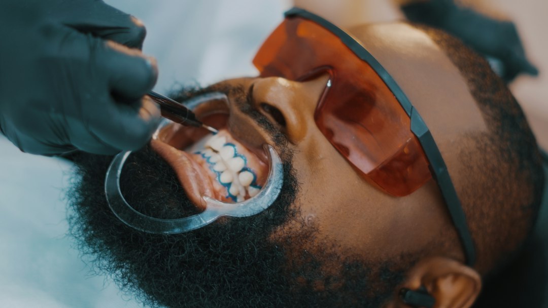 Dentist cleaning a patient's teeth in the dental chair