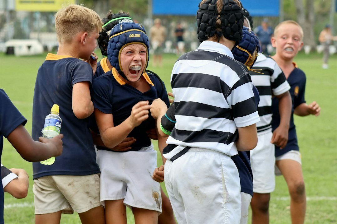 Young boys in rugby gear celebrating on a field